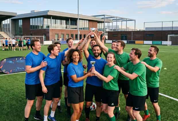Colleghi che sollevano una coppa dopo aver vinto nel team building calcio